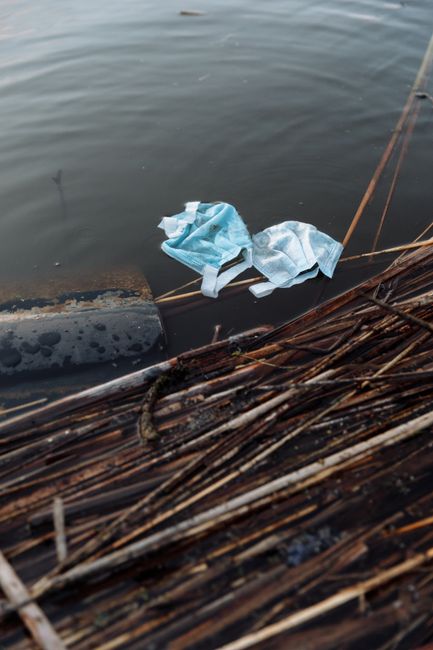 A weathered wooden frame, rectangular in shape, partially submerged in murky green water, appears to be an old, abandoned boat or container used for waste or drainage. The interior surface of the stru